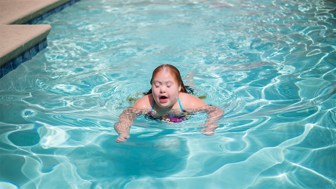 A child swims in the middle of a swimming pool.