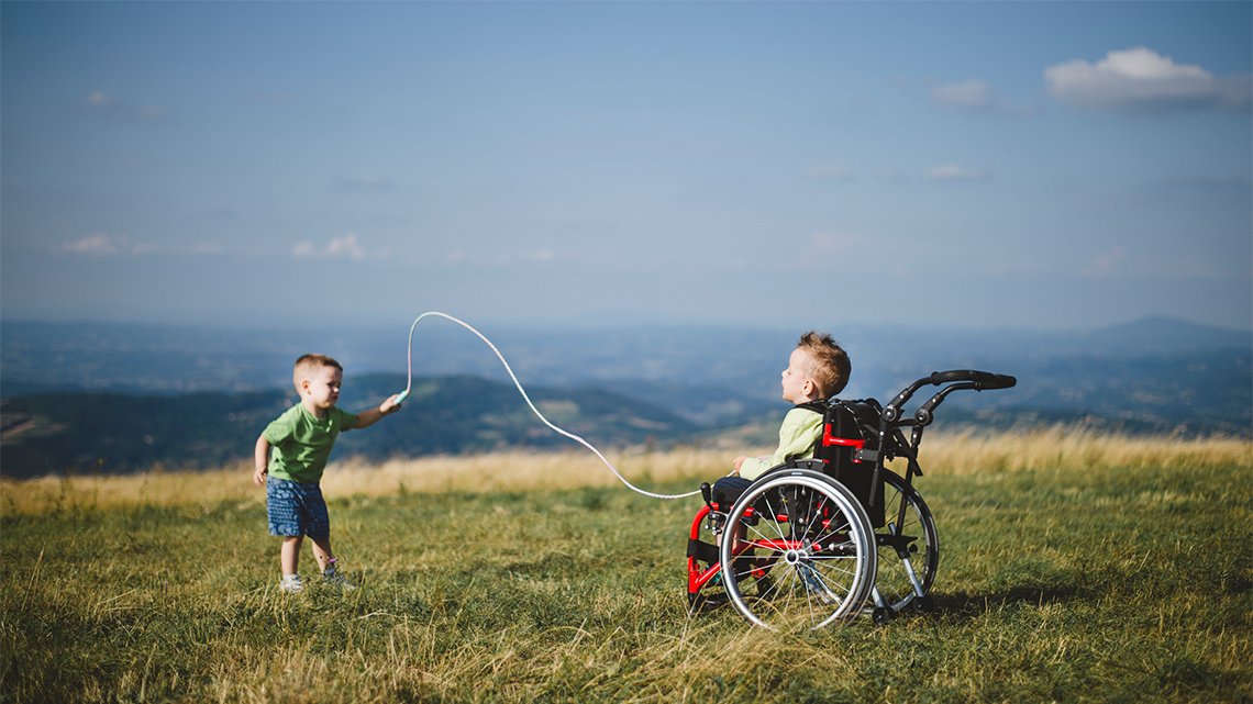 One child is standing and one child is seated in a wheelchair. They both hold one end of a skipping rope.