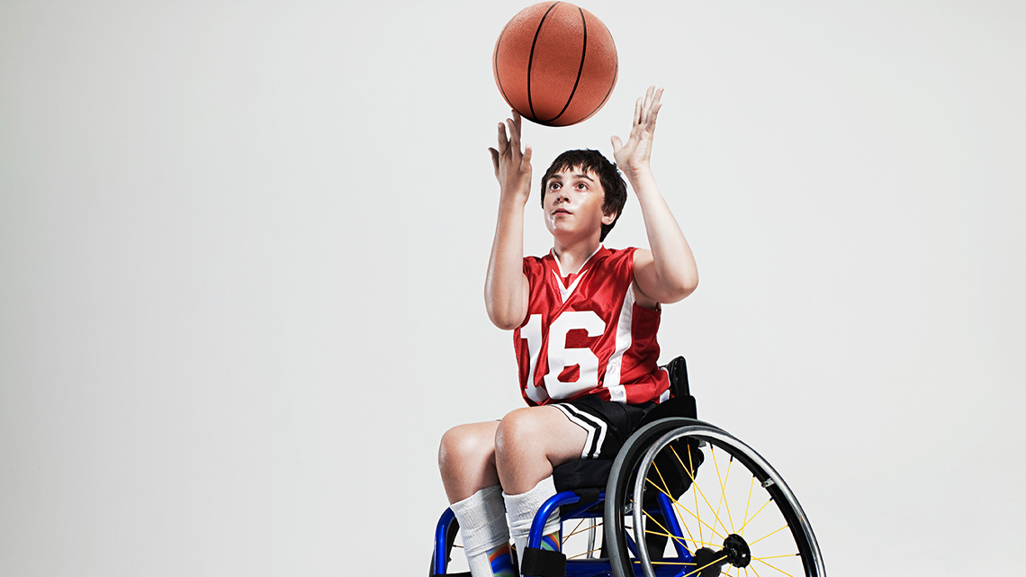 A child in a wheelchair throwing a basketball up in the air.