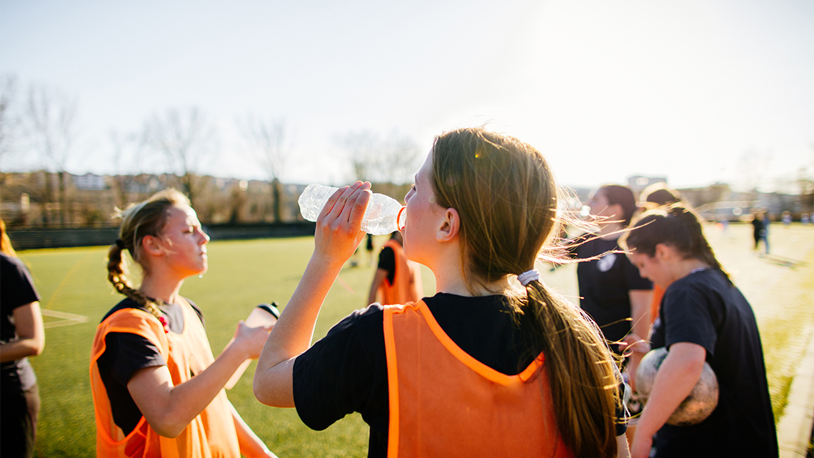 Soccer players hydrating to practice self-care while playing.