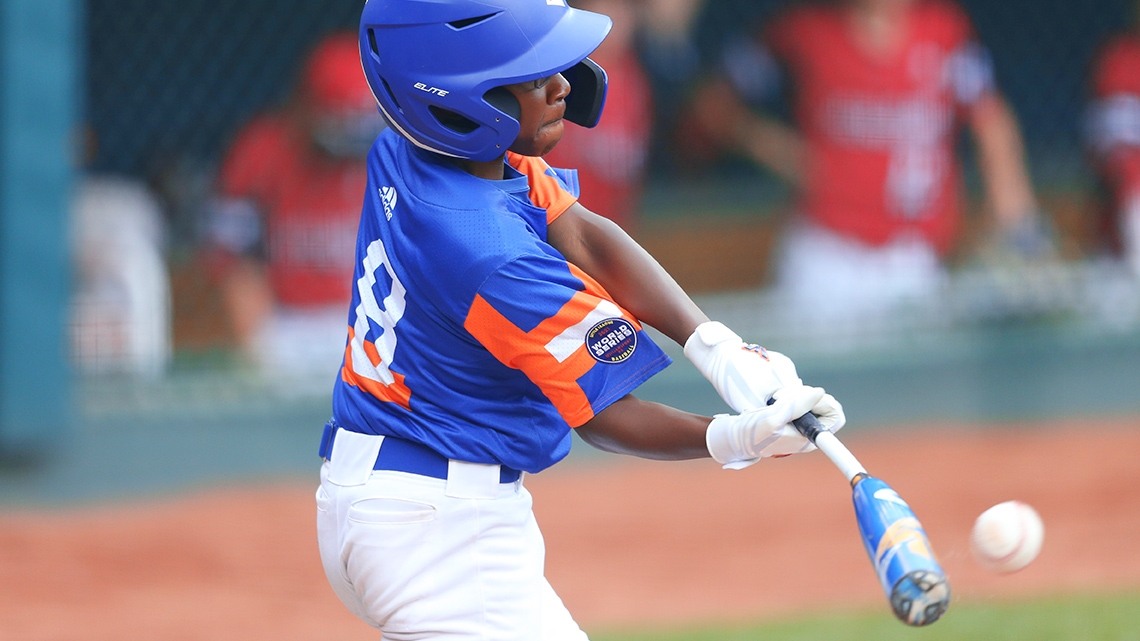 A baseball player wearing a blue batting helmet and white gloves swinging the bat to hit the baseball.