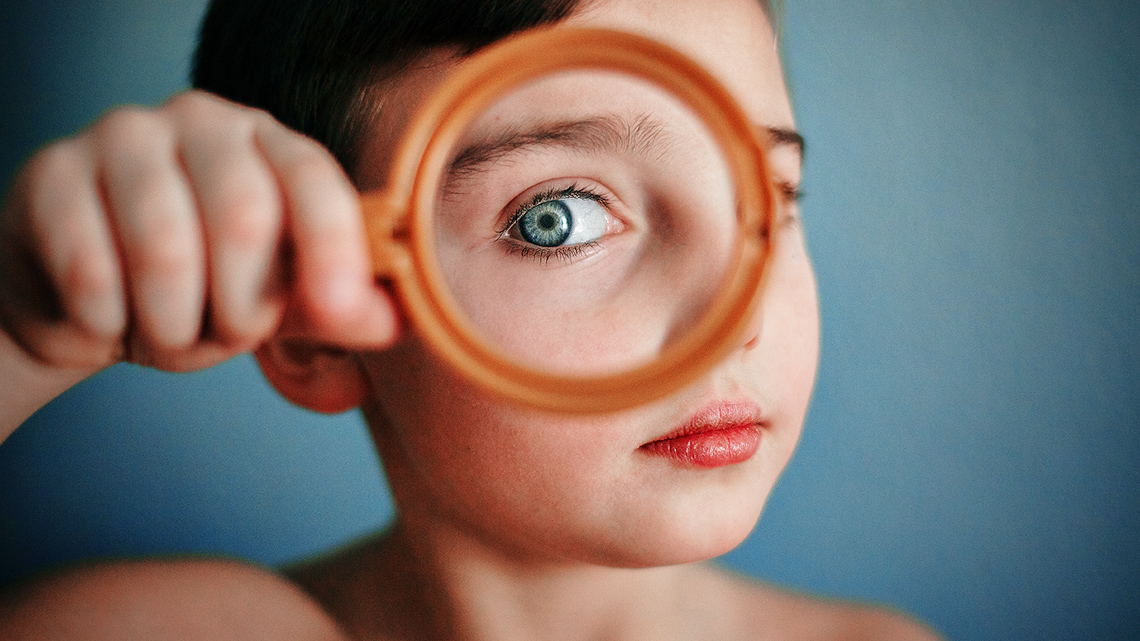 A child looking through a magnifying glass.