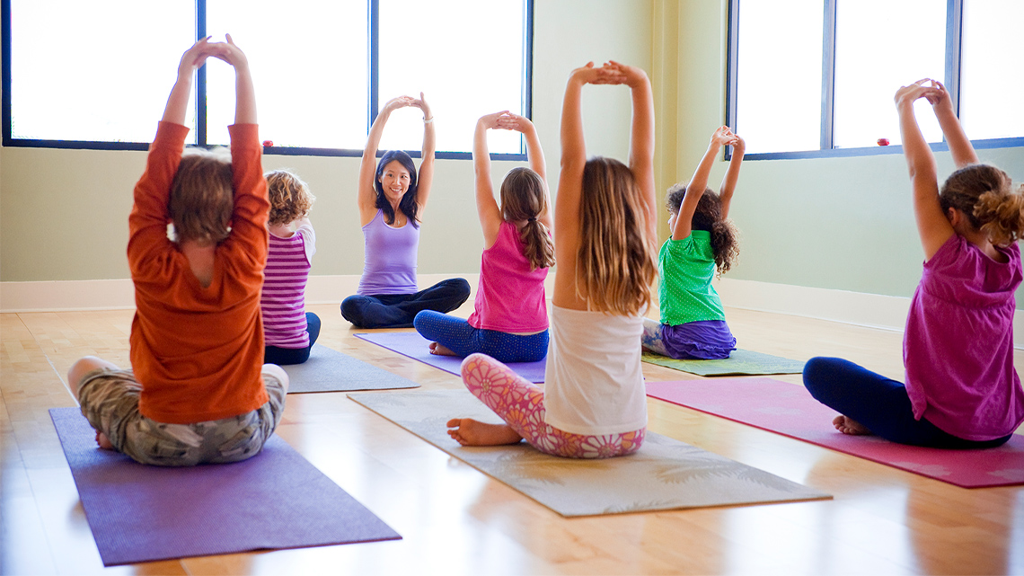 A group of children practice yoga.