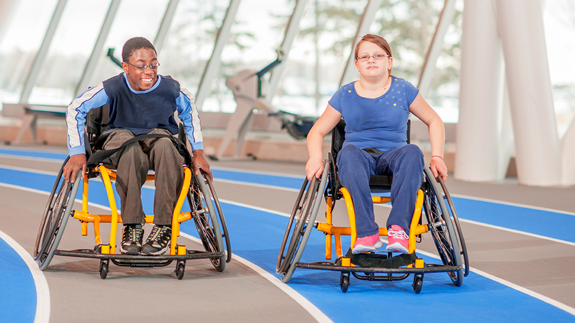 Two children in wheelchairs at a gym