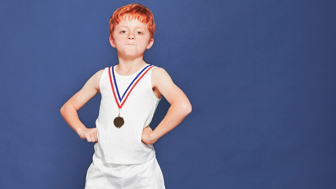 A child wearing a medal and standing with their hands on hips