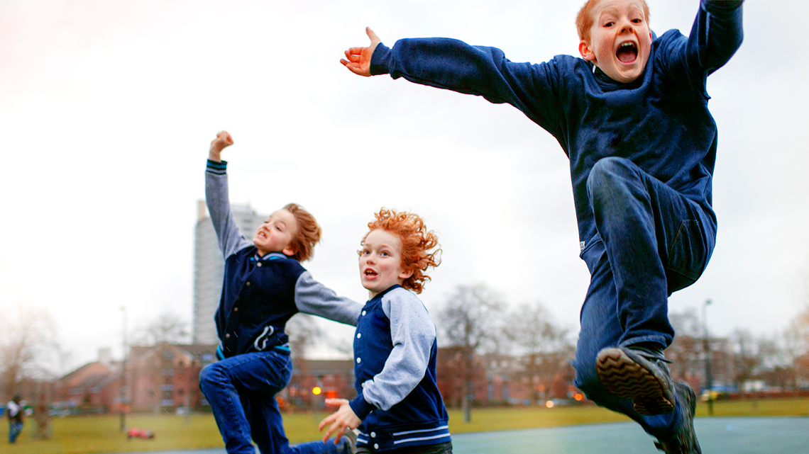 Three children excitedly jumping in the air.