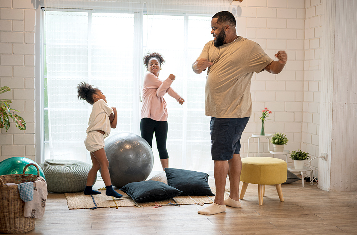 An adult and two children doing arm stretches.