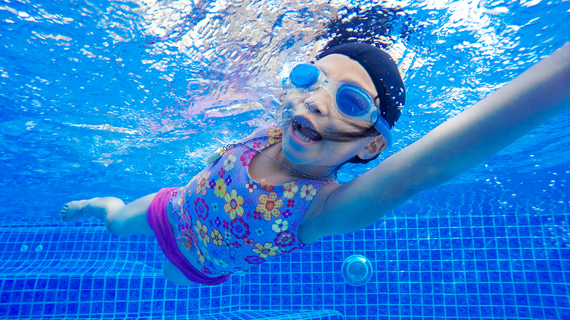 A child is swimming, photographed under water. 
