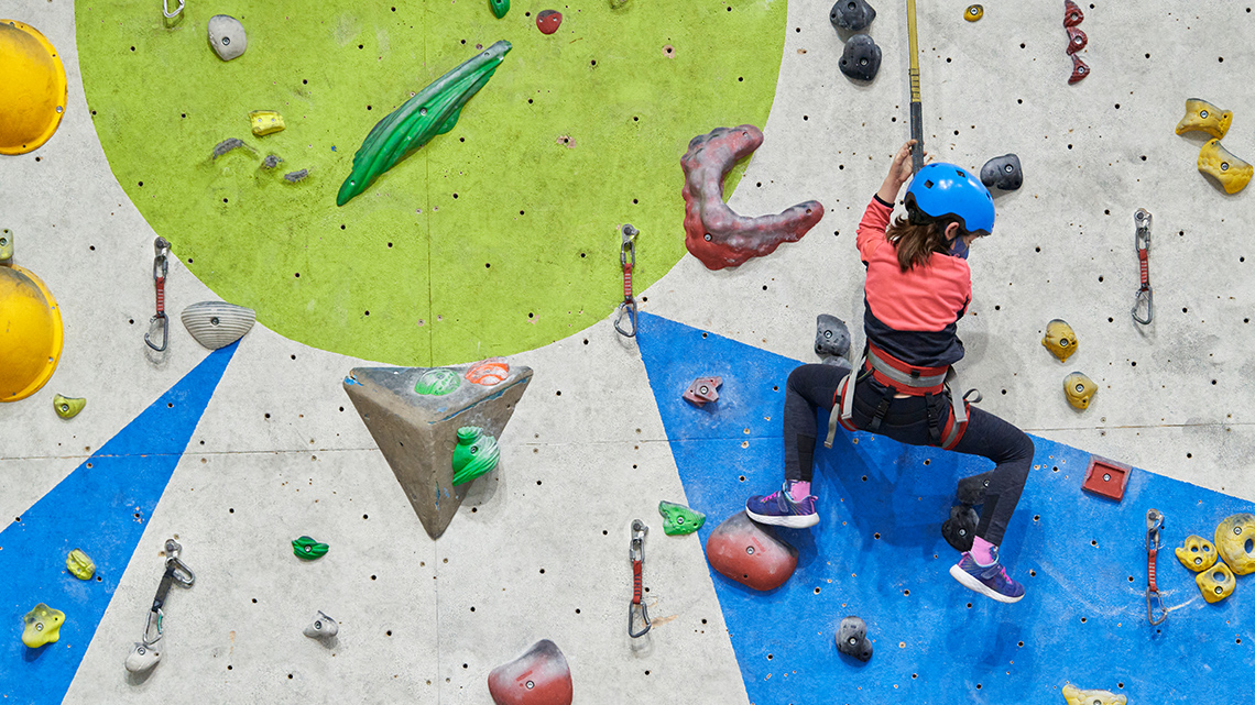A child doing some indoor rock climbing.