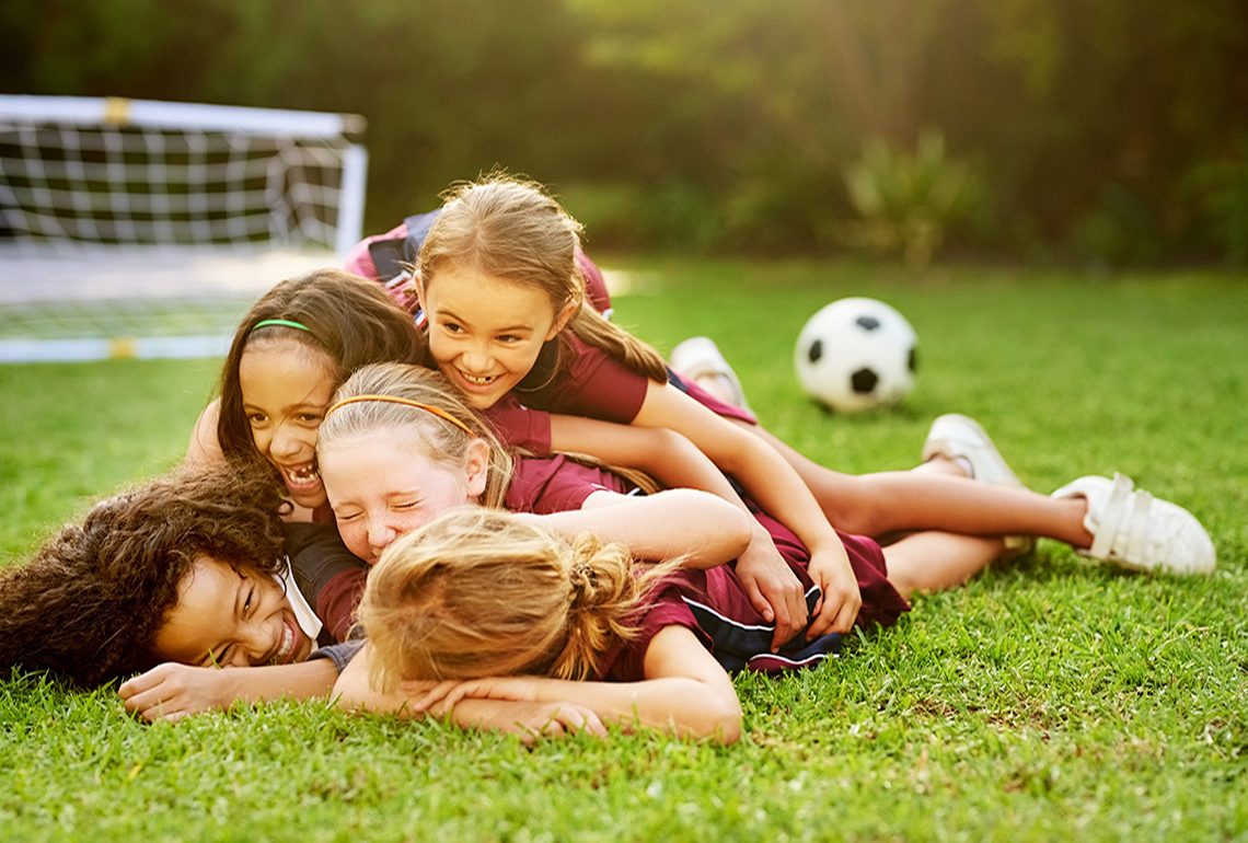 Children piling on each other at a soccer game.