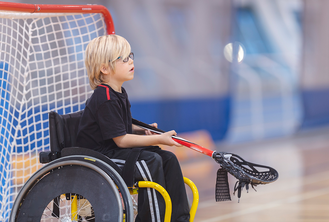 A child who uses a wheelchair playing lacrosse.