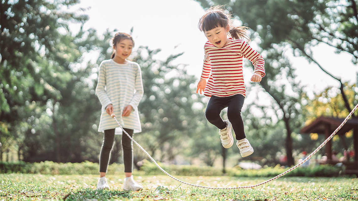 Two children jumping rope together.