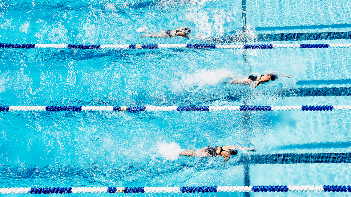People are swimming in the lanes of a pool.