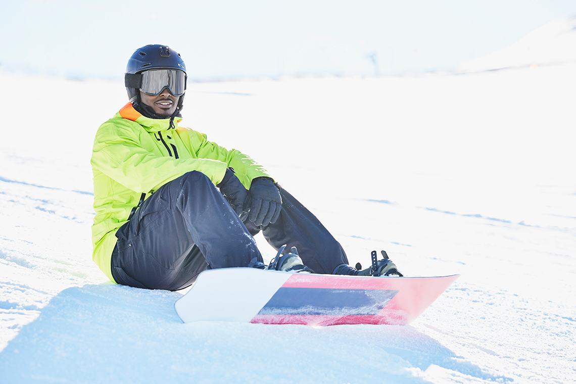 Snowboarder wearing safety equipment, which includes a helmet, eyewear, and special clothing to keep them warm.