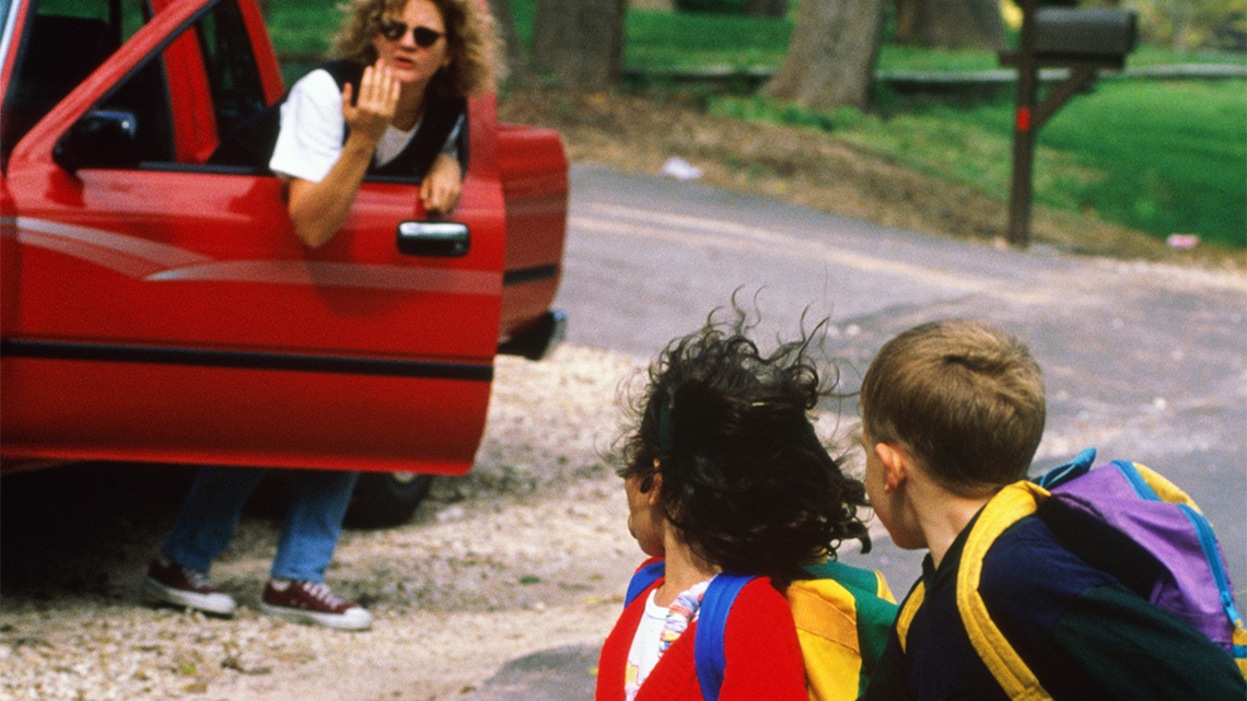 A stranger in a car tries to talk to two children.