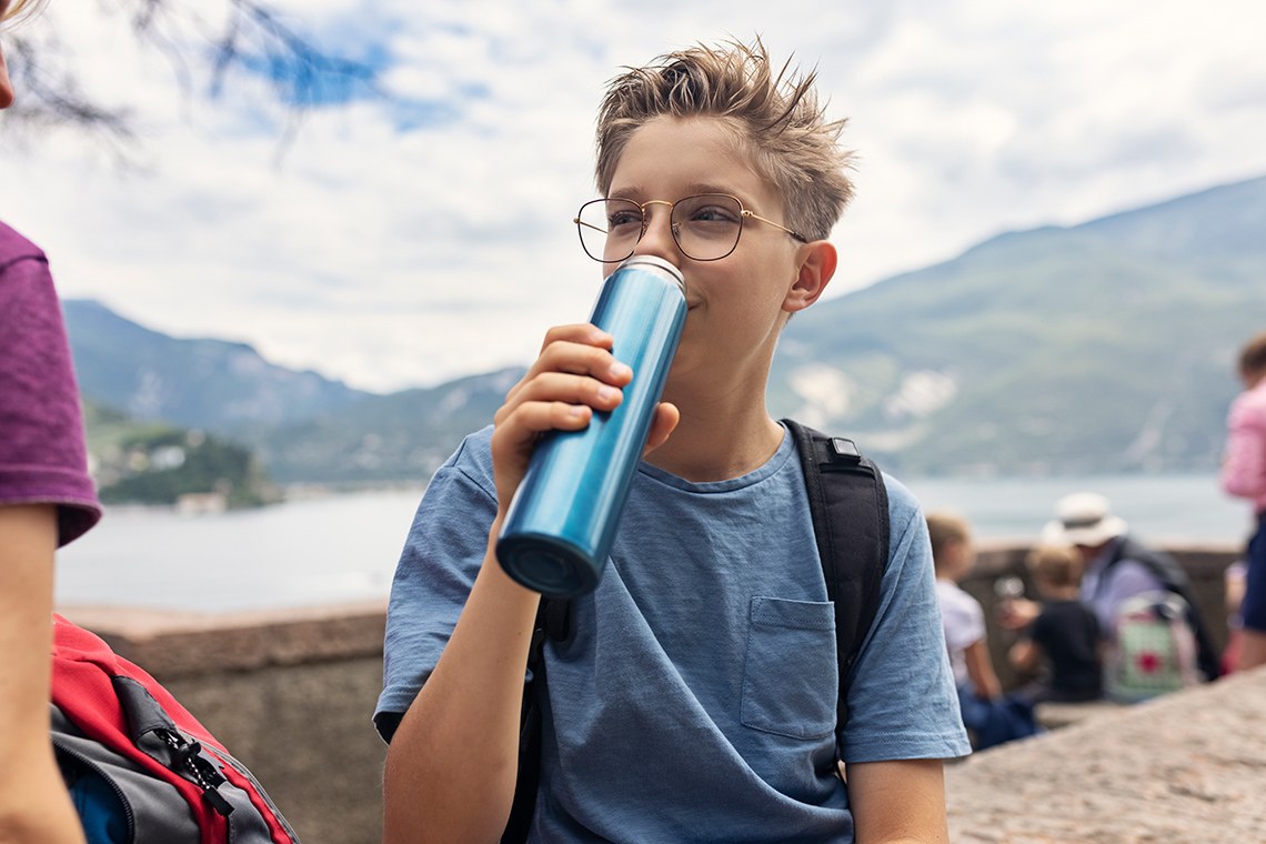 A learner drinks from a reusable bottle outside.