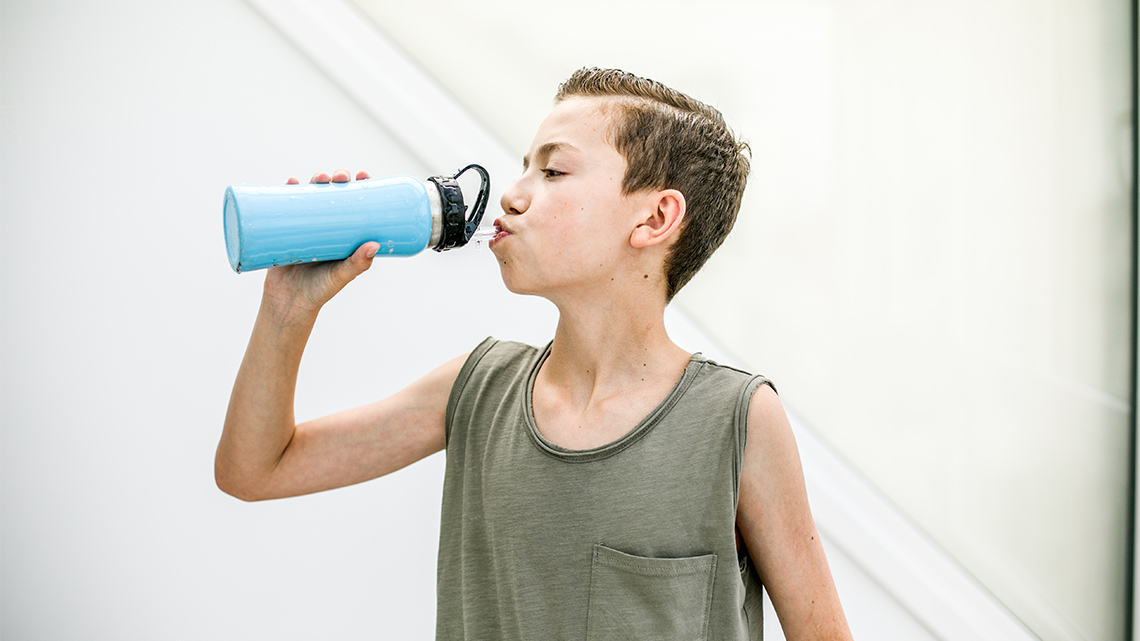 A person drinks from their reusable water bottle.