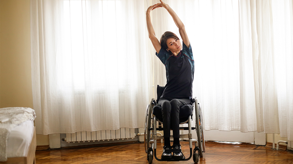 A person stretches her arms above her head for a static stretch.