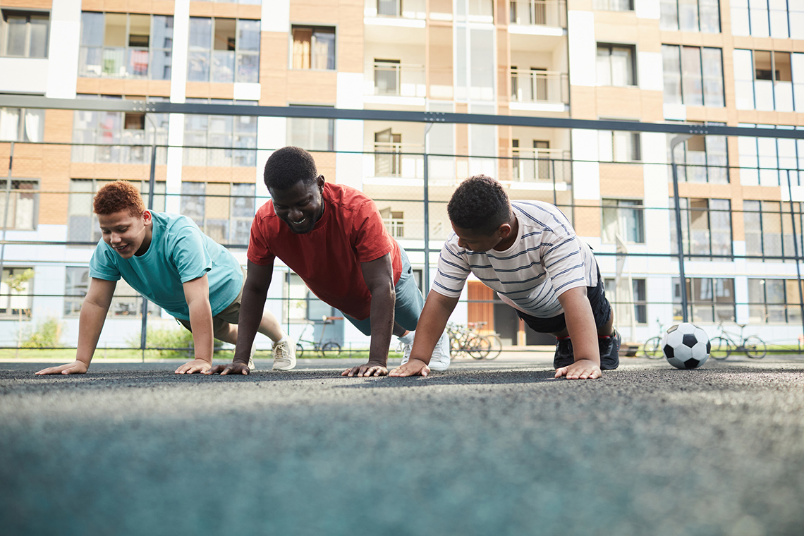 Student in gym class performing a body weight exercise, push ups with peers.