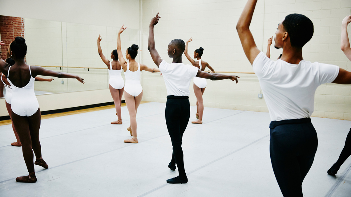 Ballet students practising with their teacher in a studio.