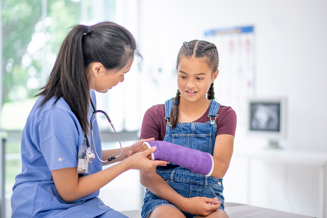 Child with a hand cast visiting the doctor for a check up.
