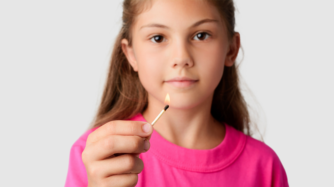 A child holding a lit matchstick.