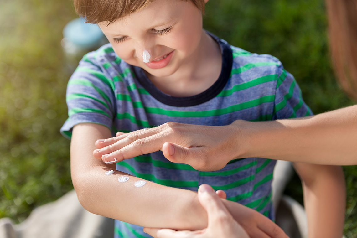 A child having sunscreen applied by an adult.