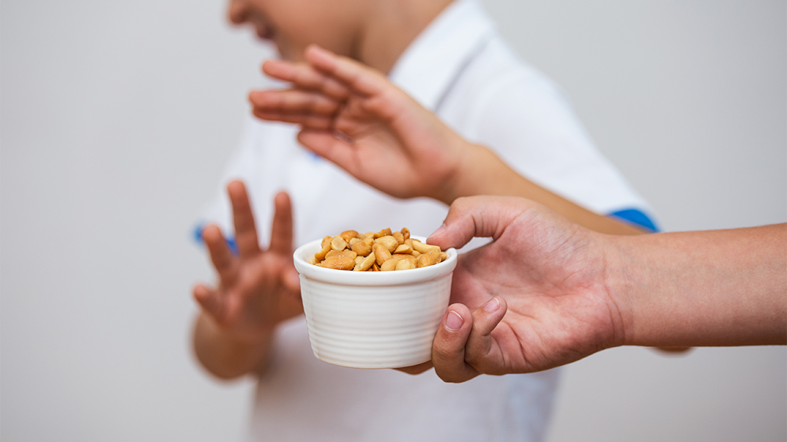 A child gesturing to keep peanuts away from them.