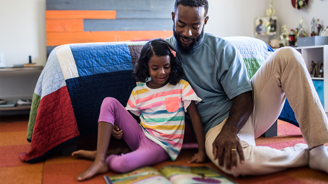 A child looking at a picture book that an adult is reading to them.