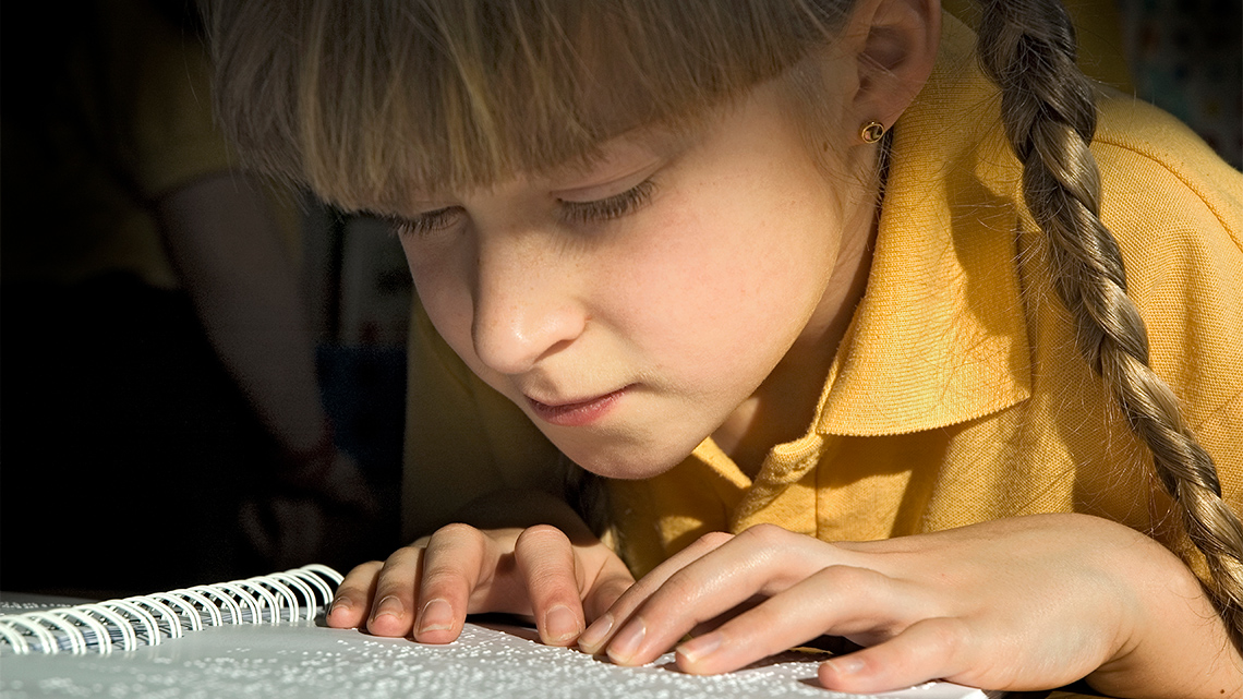 A child is using their fingers to read braille