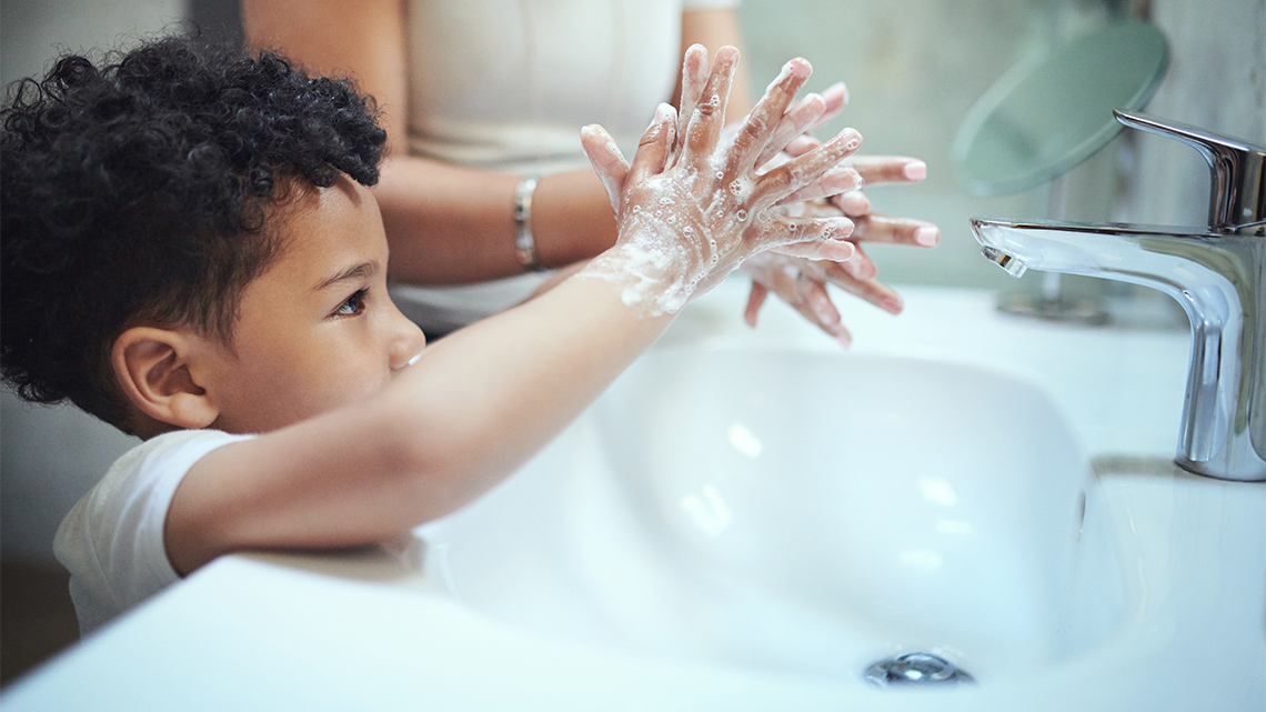 A child washing their hands with soap at a sink.