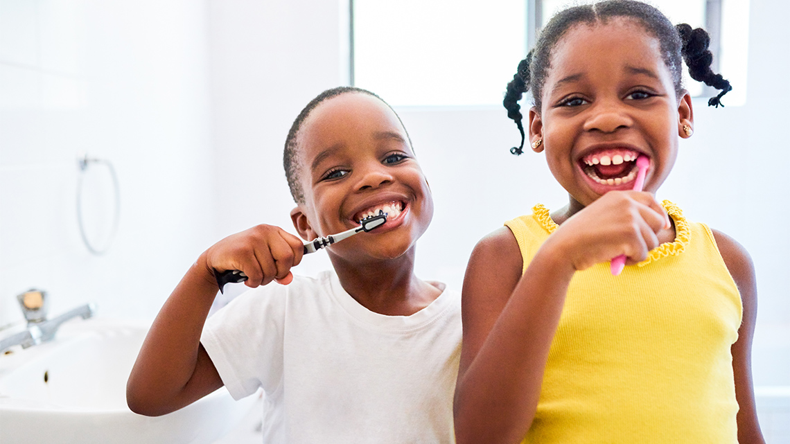 Two children brush their teeth in a bathroom.