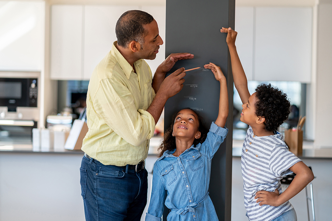 Image of a child having their height measured by a parent.