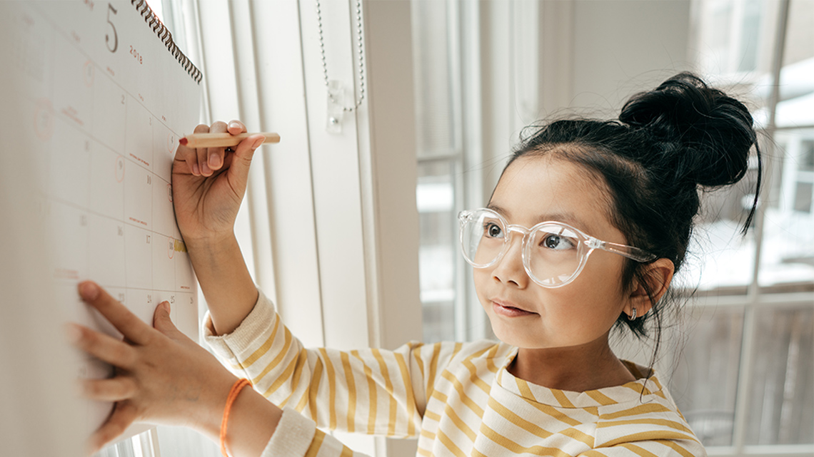 A child writing on a calendar.