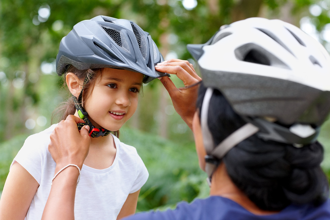 A parent puts on their child’s bike helmet.