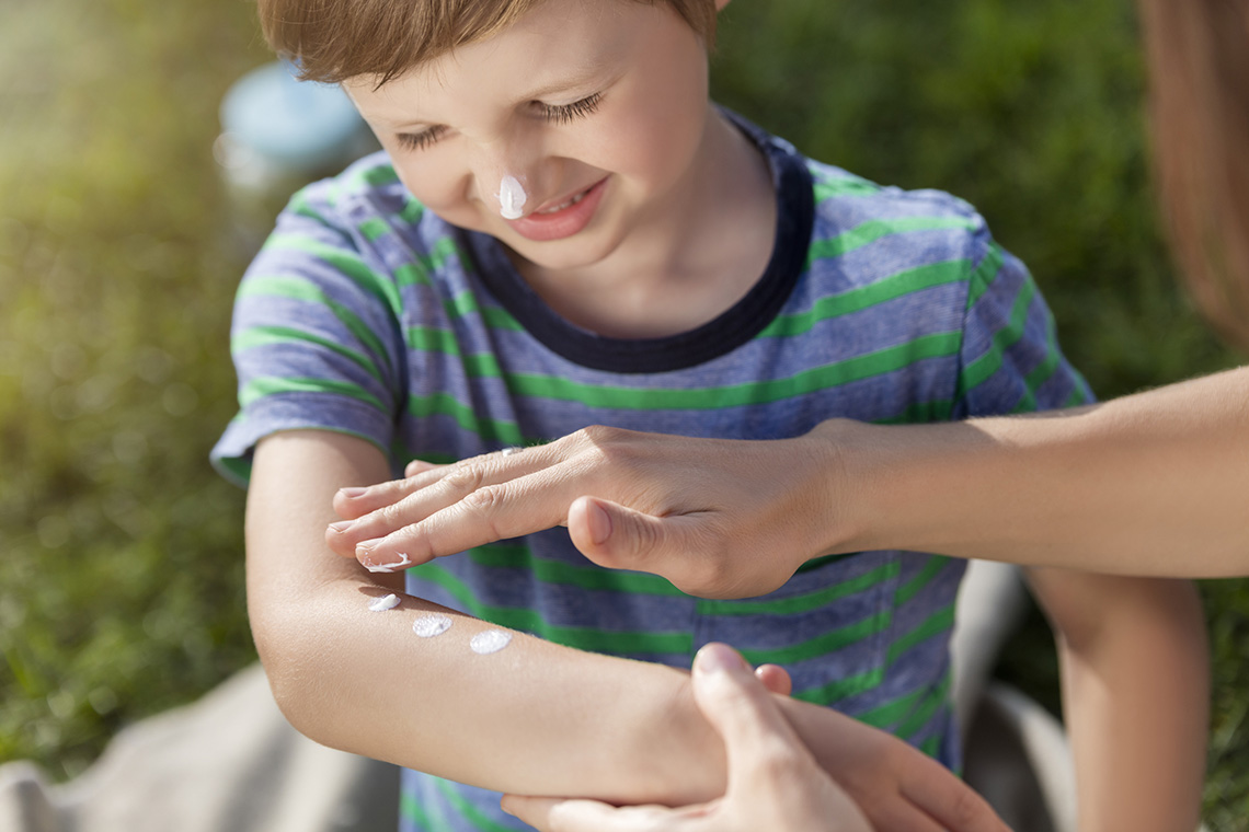 An adult applying sunscreen to a child's arm.