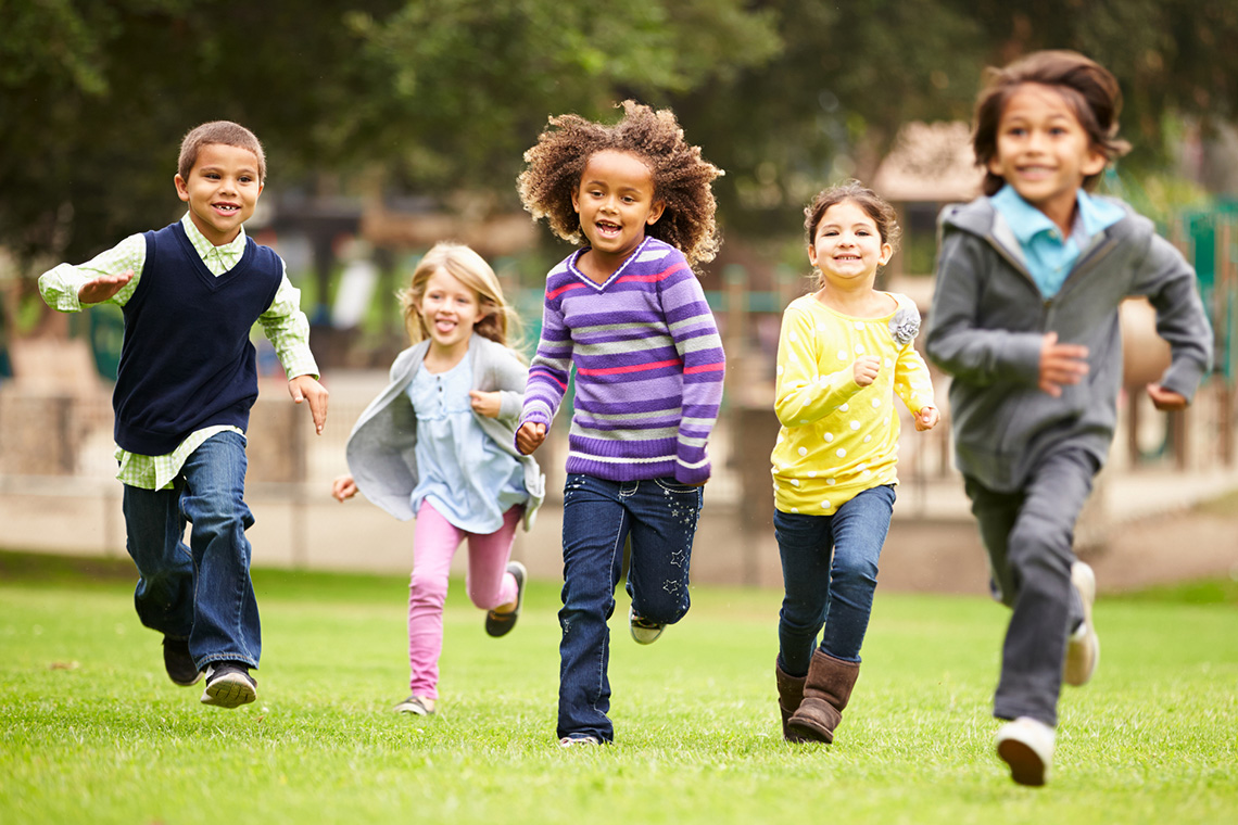 Five children running together on a playground.