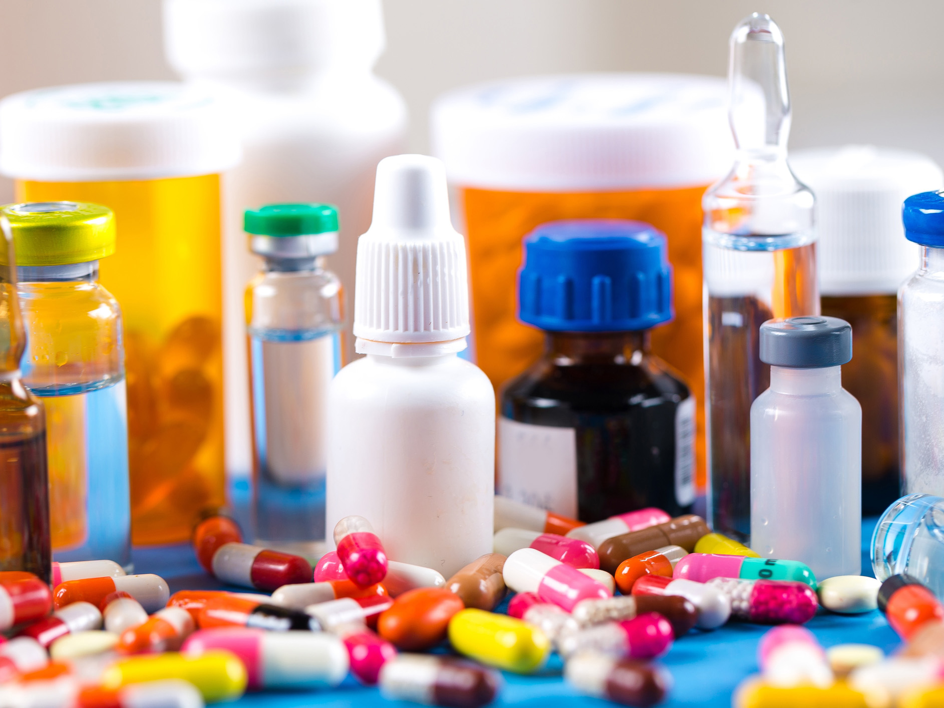 A variety of pills, vials of liquid, and medication bottles on a surface.
