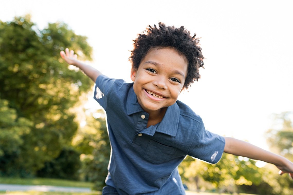 A smiling child in a natural space.