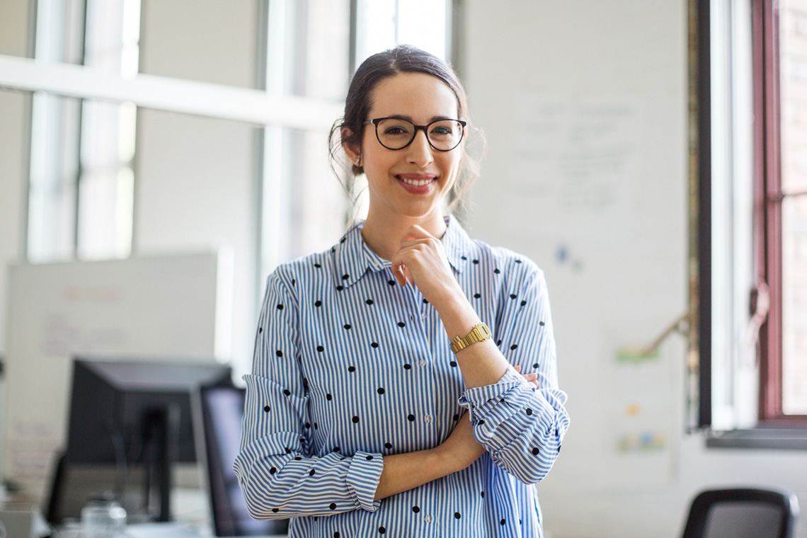 A smiling adult wearing glasses.