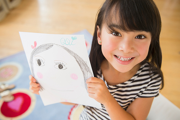 A child showing a picture of themselves that they drew.