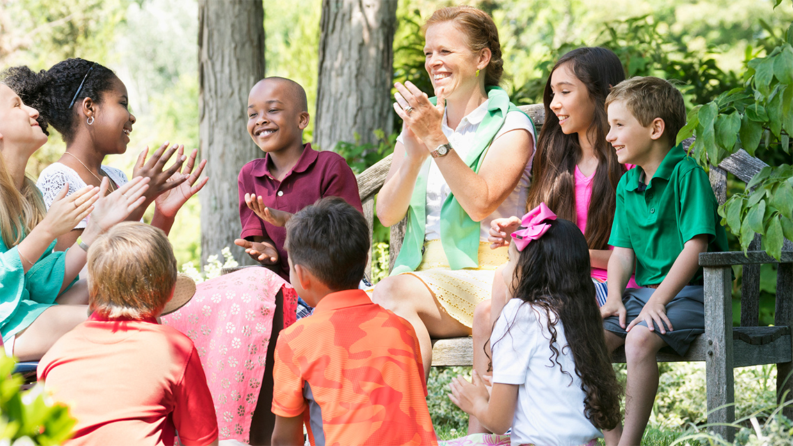 Children sitting in a circle and clapping for each other.