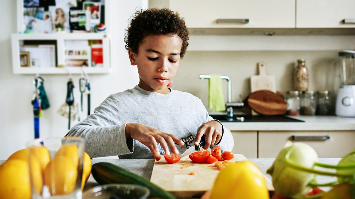 A child chopping up some vegetables.