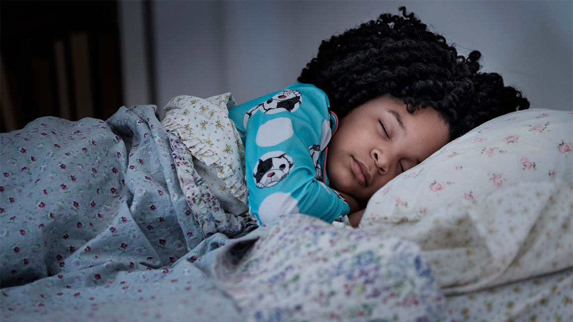 A child asleep in their bed.