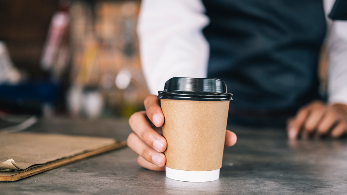 A person holding a paper cup of coffee.