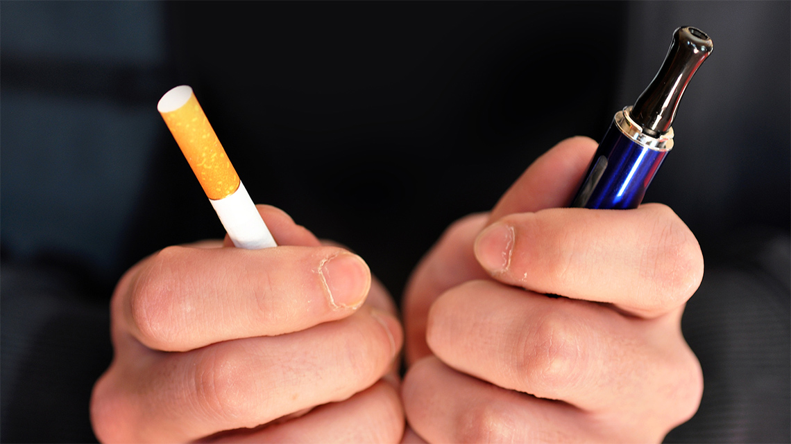 Someone holding a cigarette in one hand and a vape in the other hand.