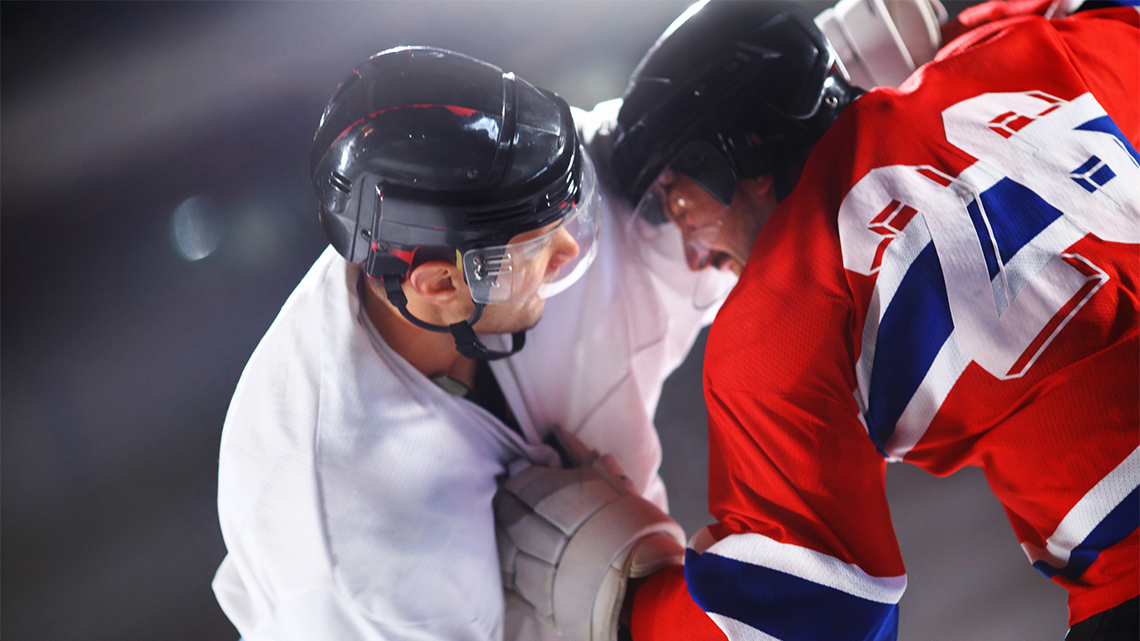 Two hockey players fighting each other on the ice.