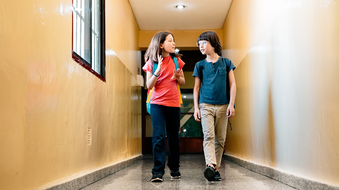 Two friends talking to each other while walking in the hallway