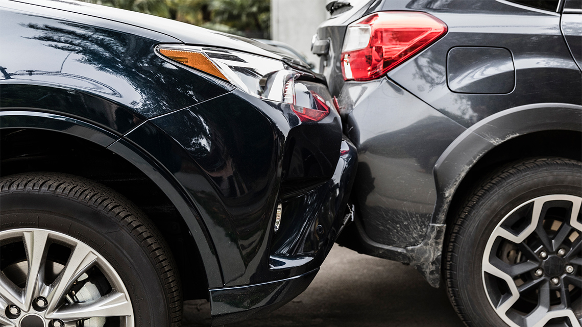 A car smashes into the back of another car. Both cars are damaged.