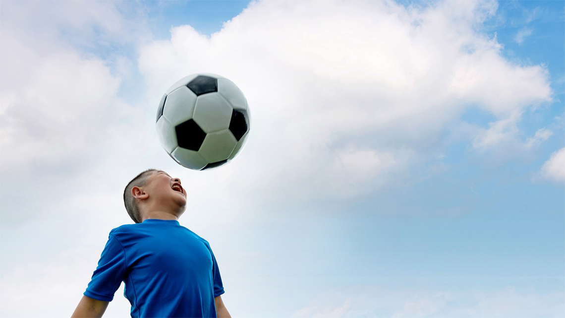 Child hitting a soccer ball with their head.